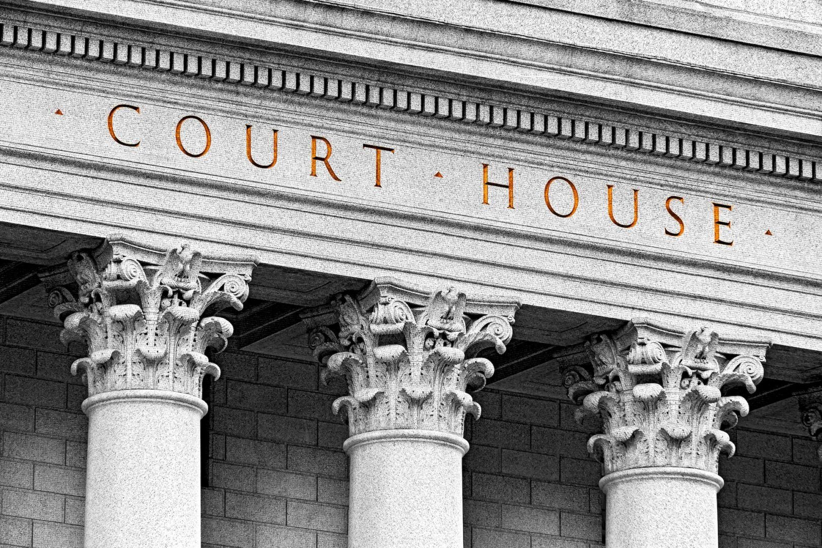 Close-up view of the facade of a courthouse, featuring ornate Corinthian columns and the words "COURT HOUSE" engraved above them. The image is in grayscale with the text highlighted in orange.